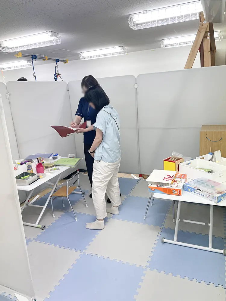 卓上の療育の説明を聞かれる先生